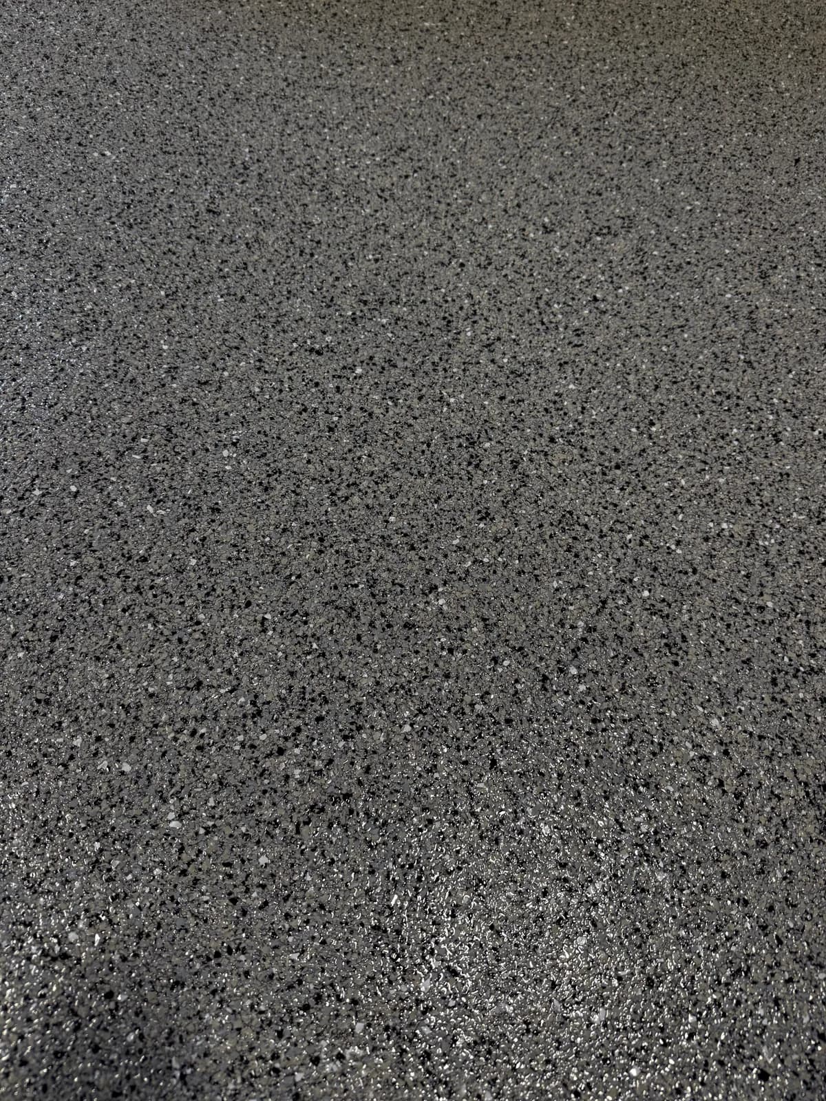 A close view of a charcoal and gray flake floor, its chips fine and densely packed, under an even matte finish