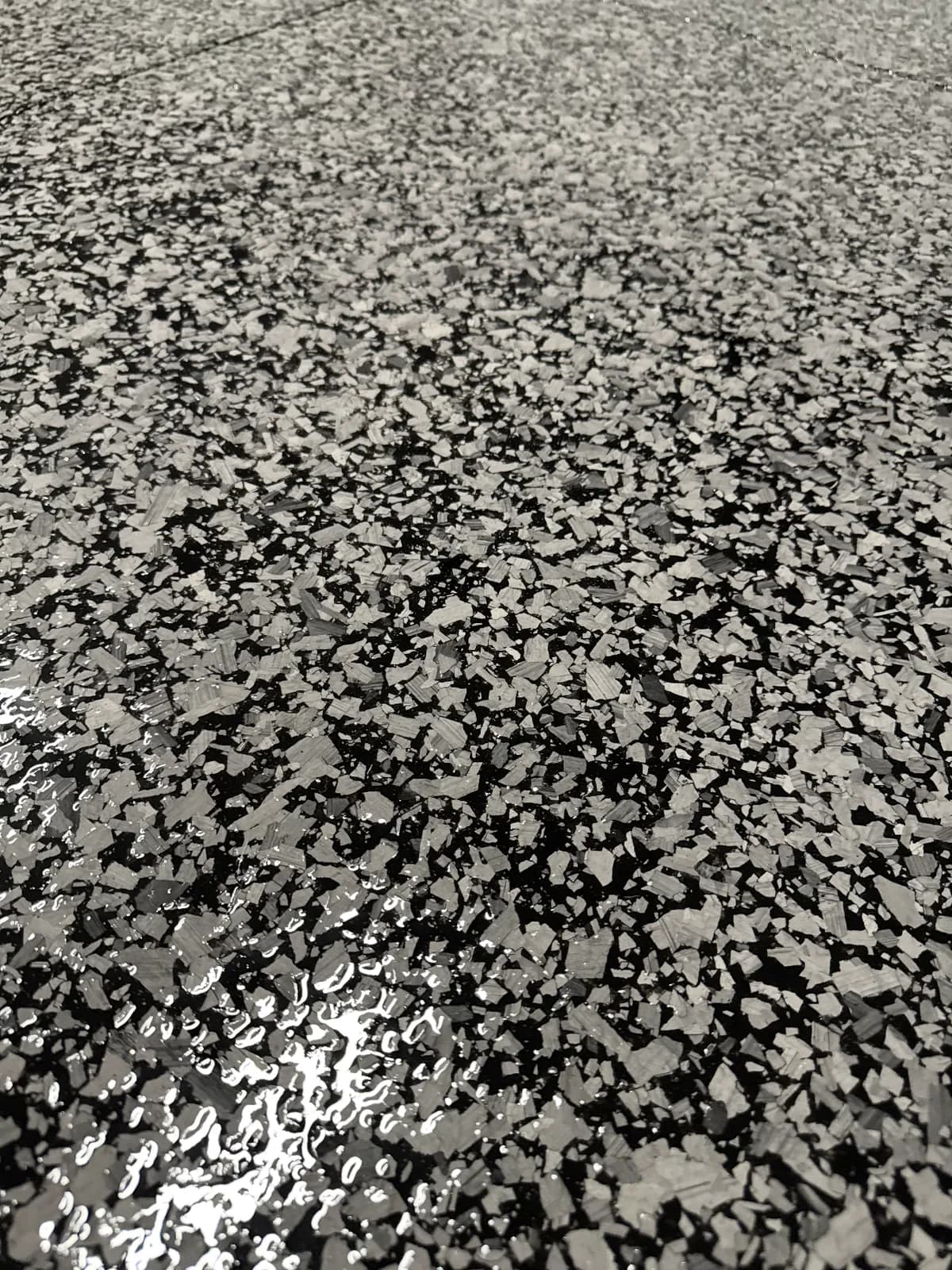 A close view of a black and silver flake floor with a pooled highlight of reflected light in the foreground