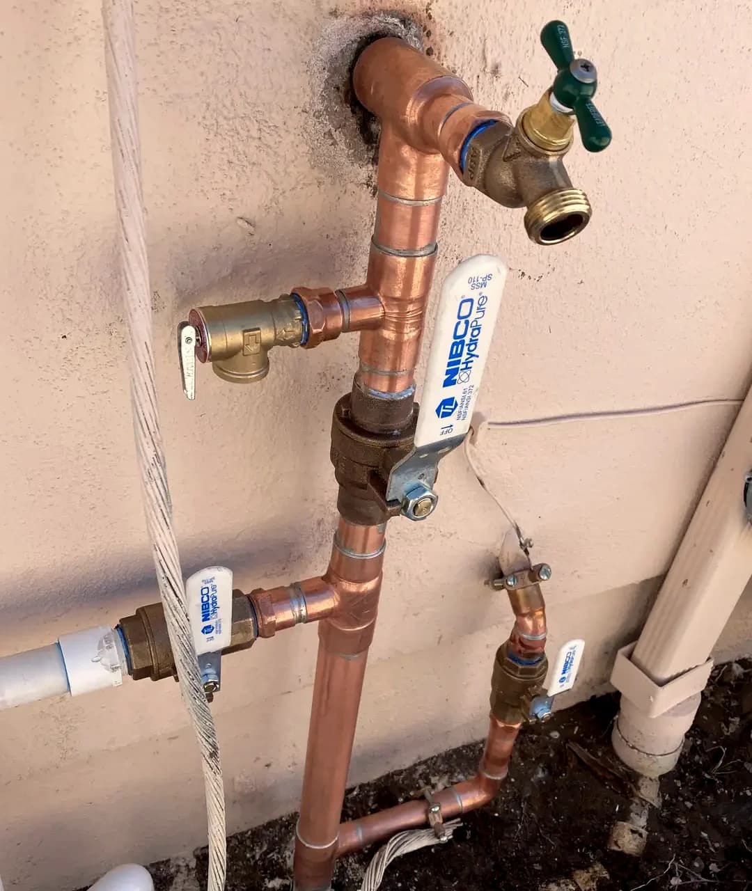 A residential water manifold and filtration tank plumbed in new copper in a clean garage