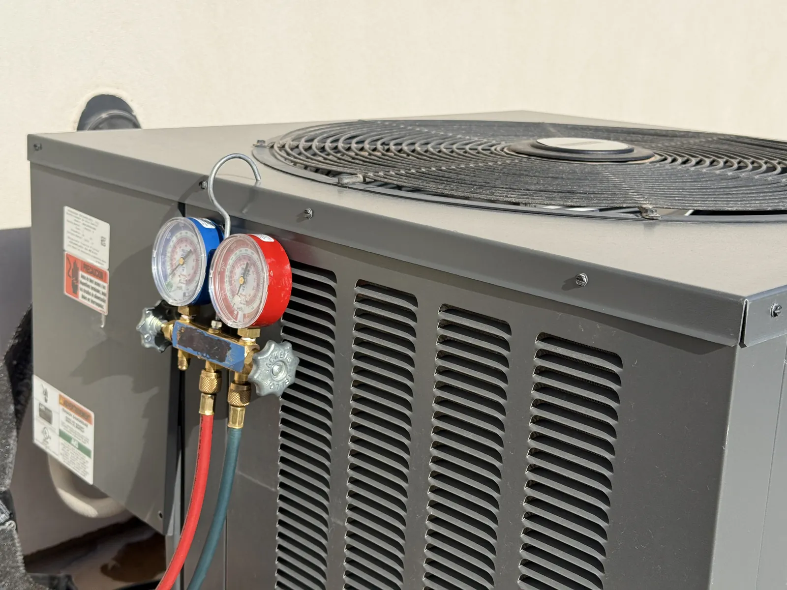 A manifold gauge set hooked to the service ports of an outdoor air conditioning condenser