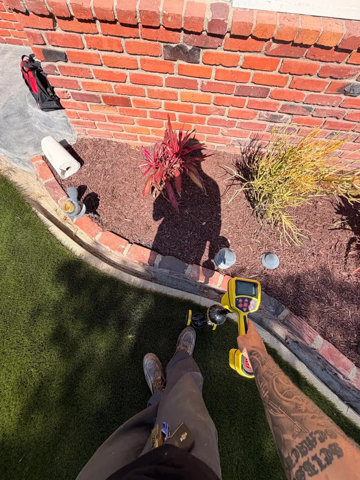 A technician holding a locator wand over the ground to mark where the camera sonde sits below