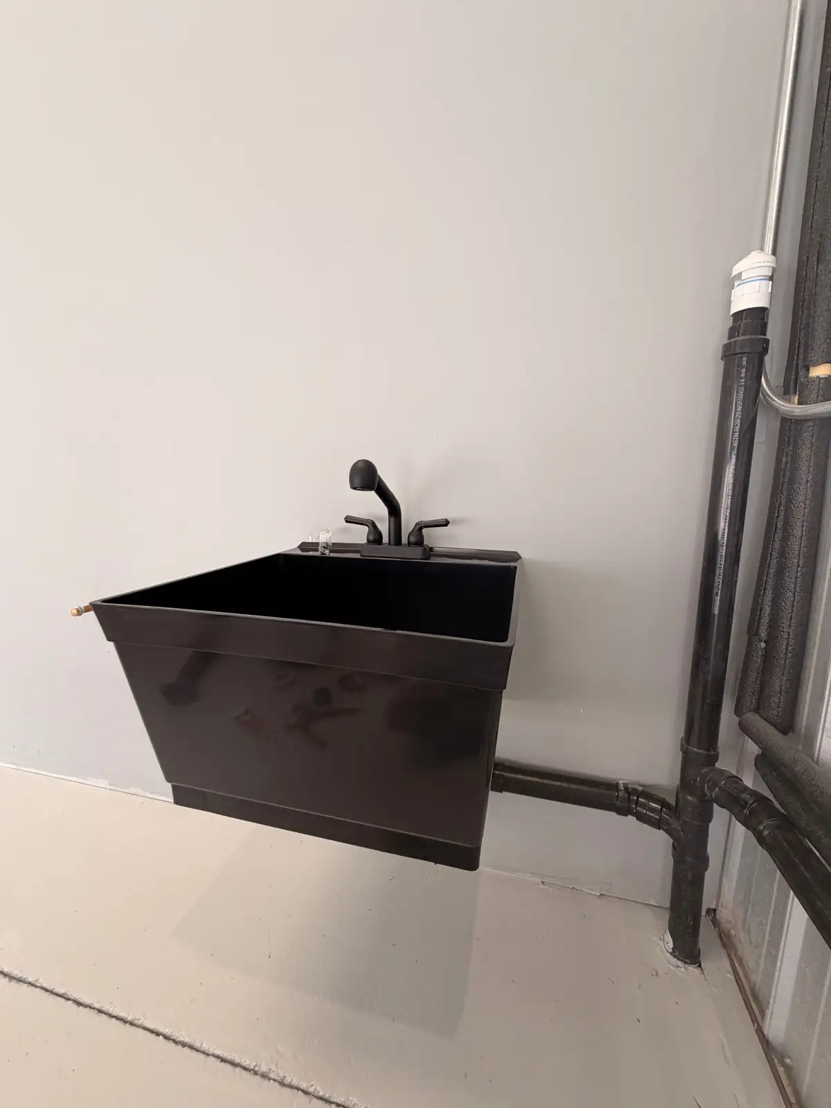 A newly installed commercial mop and utility sink with cast iron waste piping, plumbed and vented