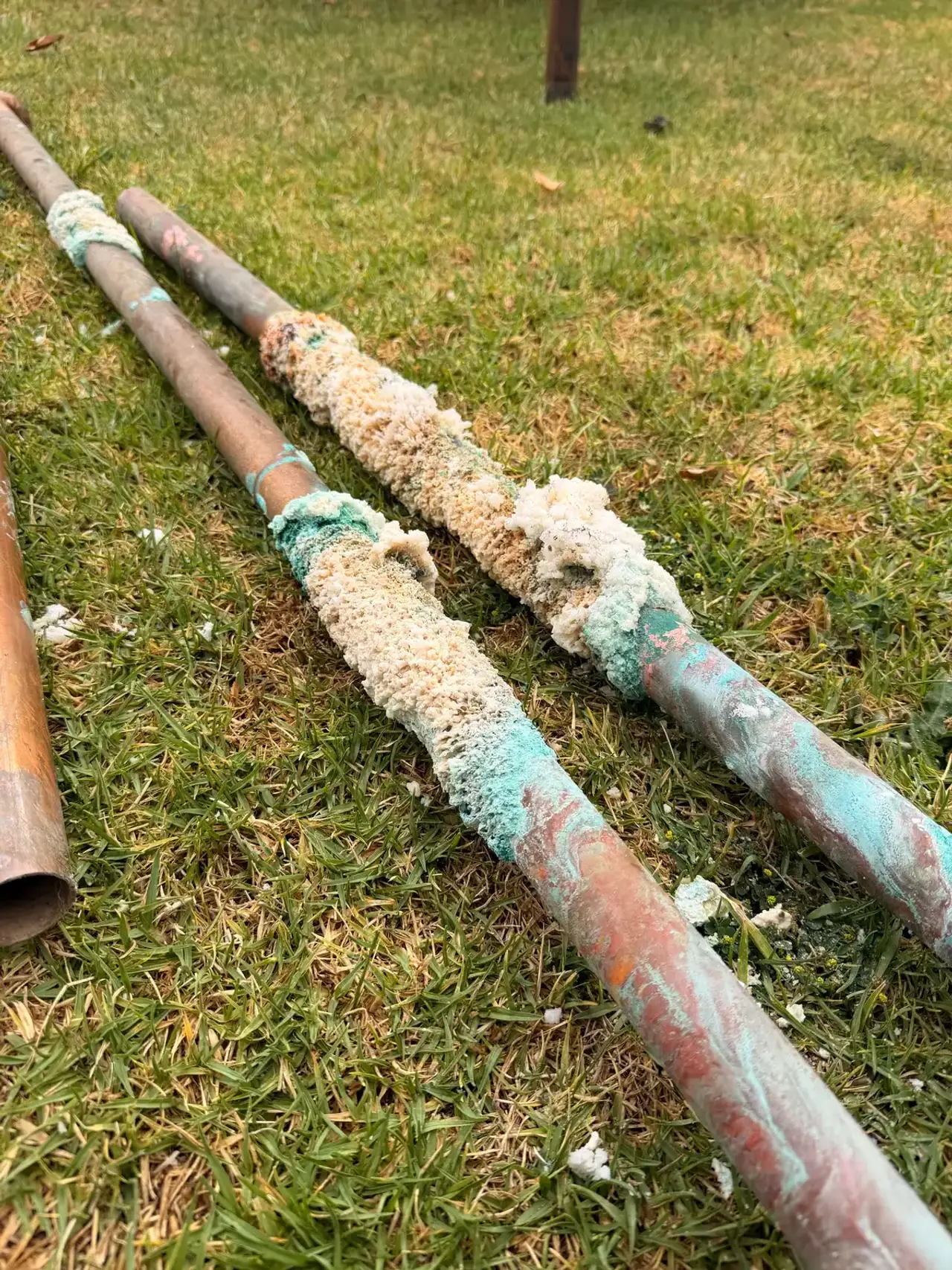 Corroded copper water line running through a crawl space, pitted along its length