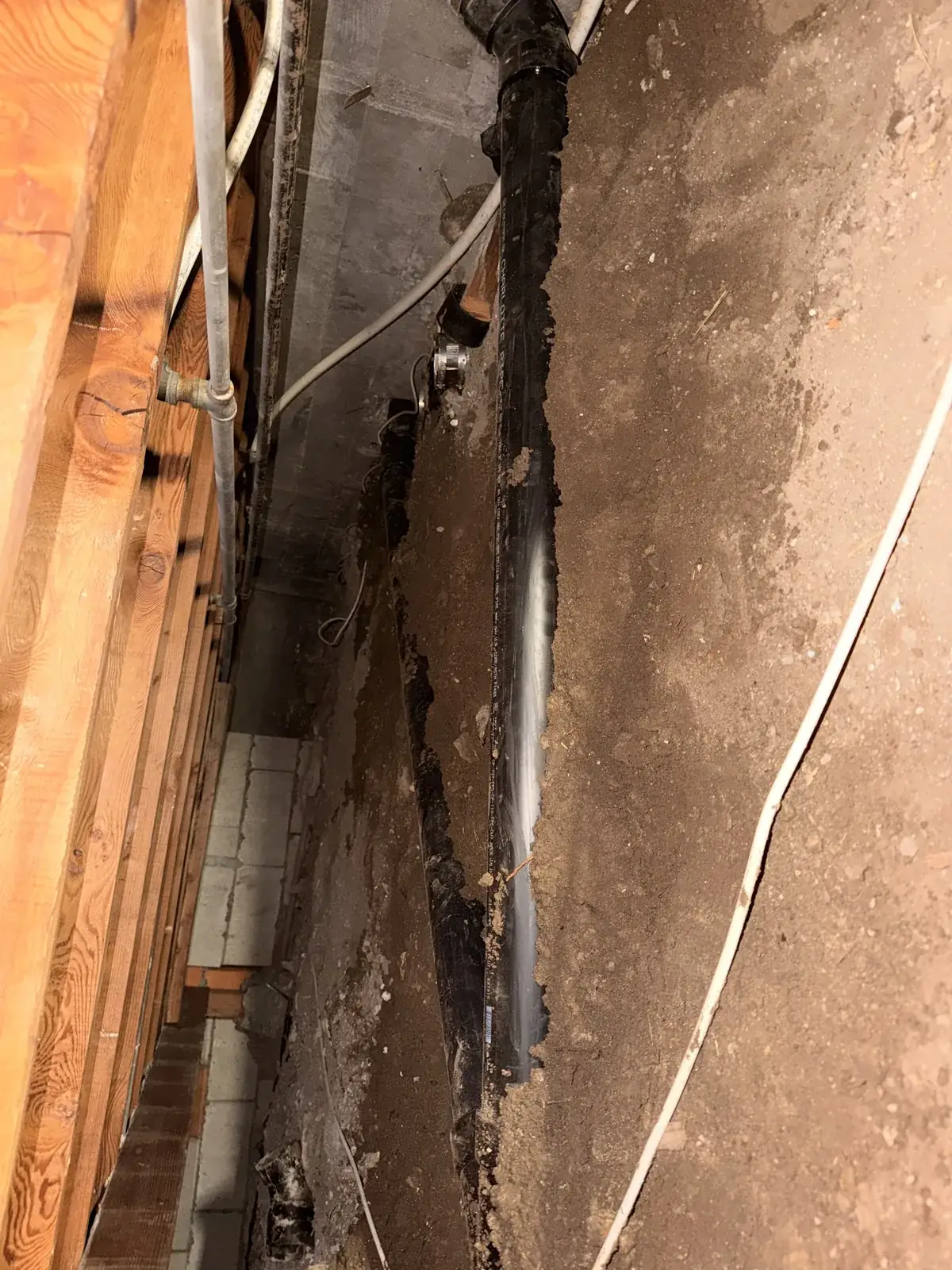 A wall opened to the studs showing a badly corroded vertical pipe running through it