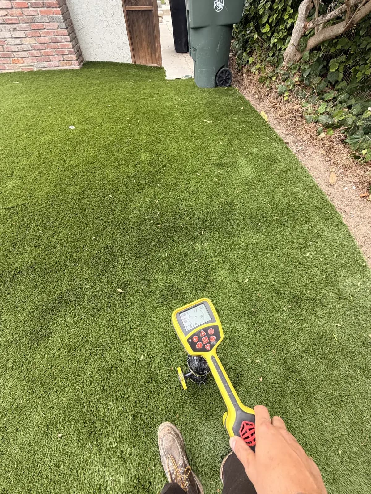 A locator wand held over a lawn, marking where the sewer line runs below
