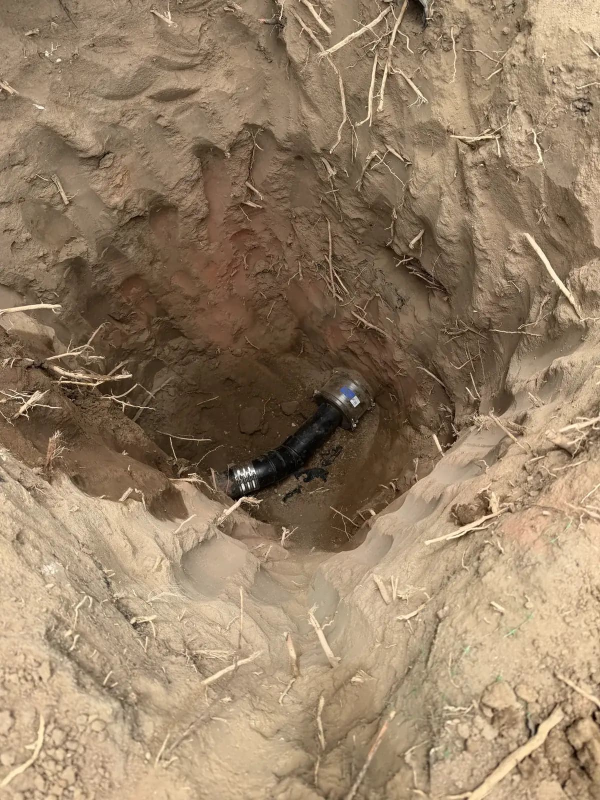 A new pipe elbow set in the base of a small excavated pit