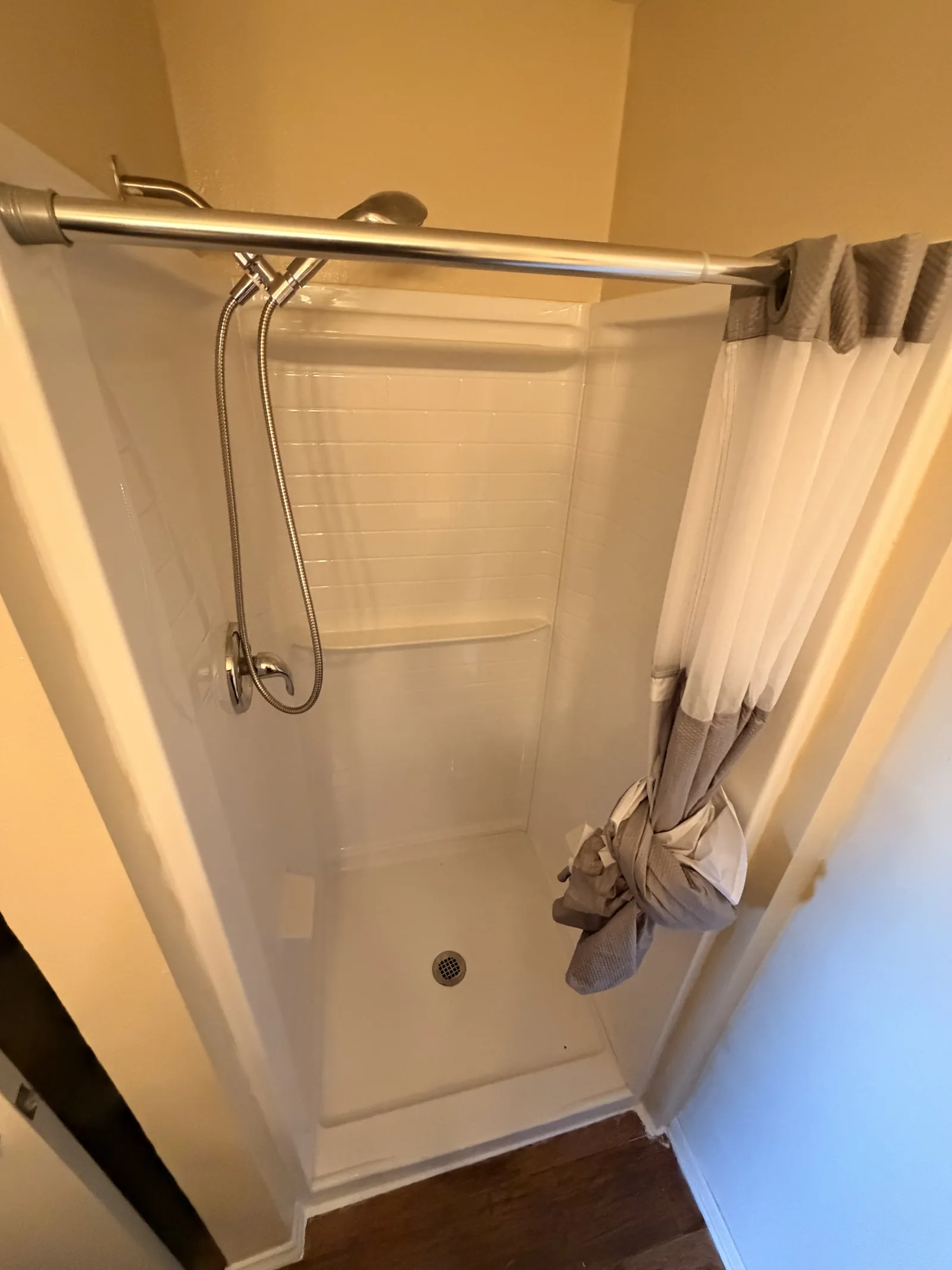 A finished walk-in shower with tiled walls, a mosaic floor and a glass panel