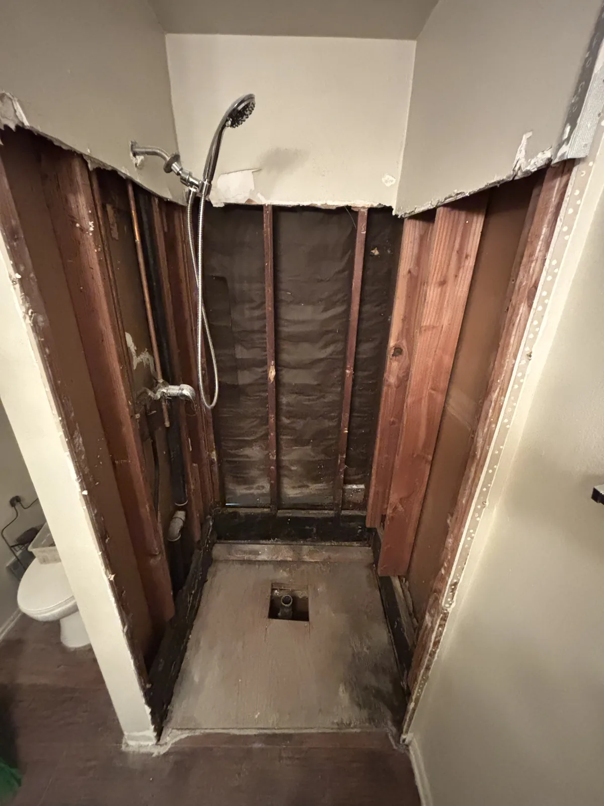 A shower stripped back to the studs, the valve set and the floor prepared