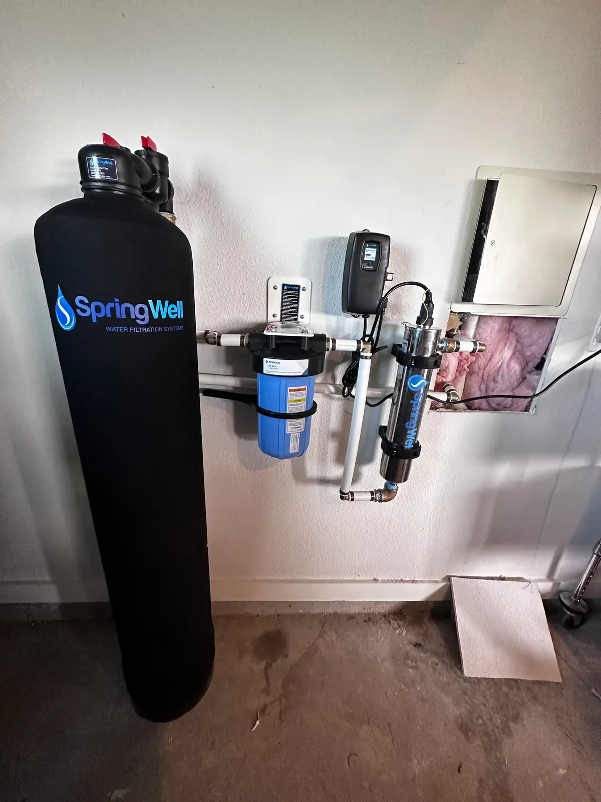A treatment system mounted on a wall with the brine tank beside it