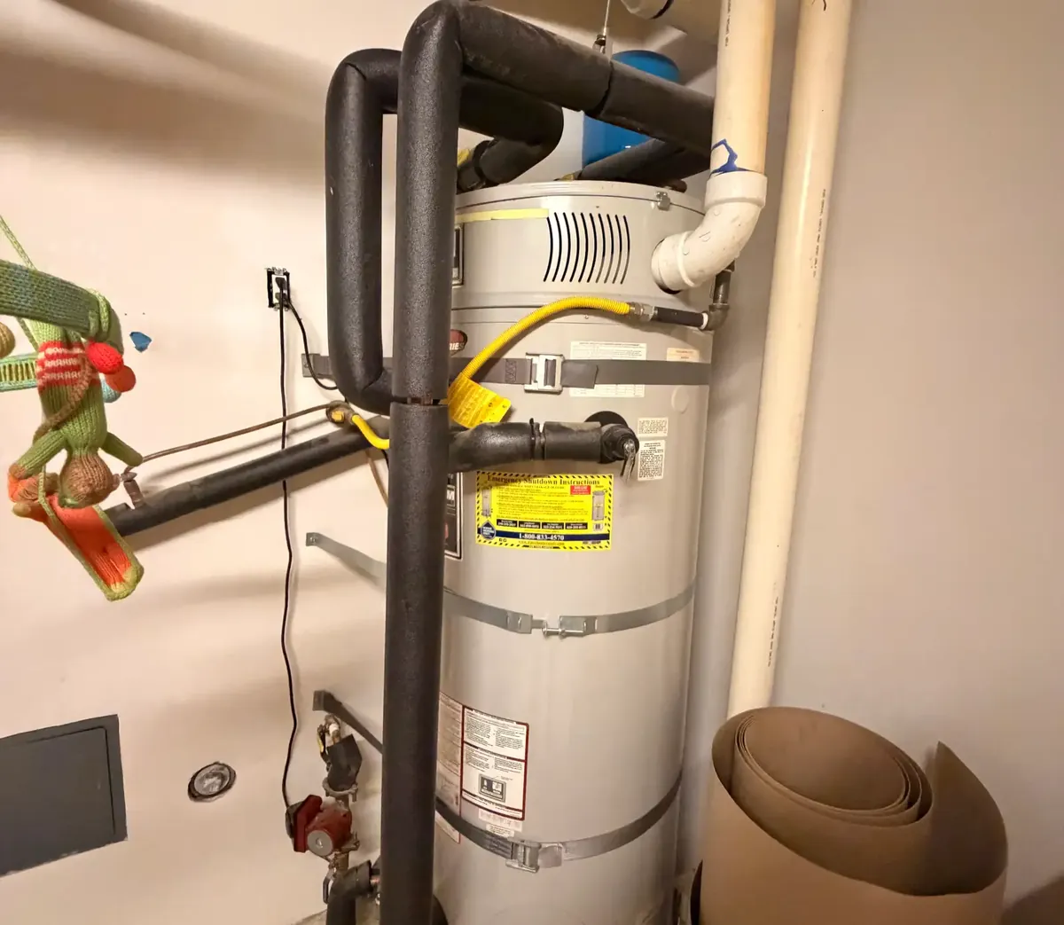 A storage water heater with two metal straps around the tank, anchored into the wall framing