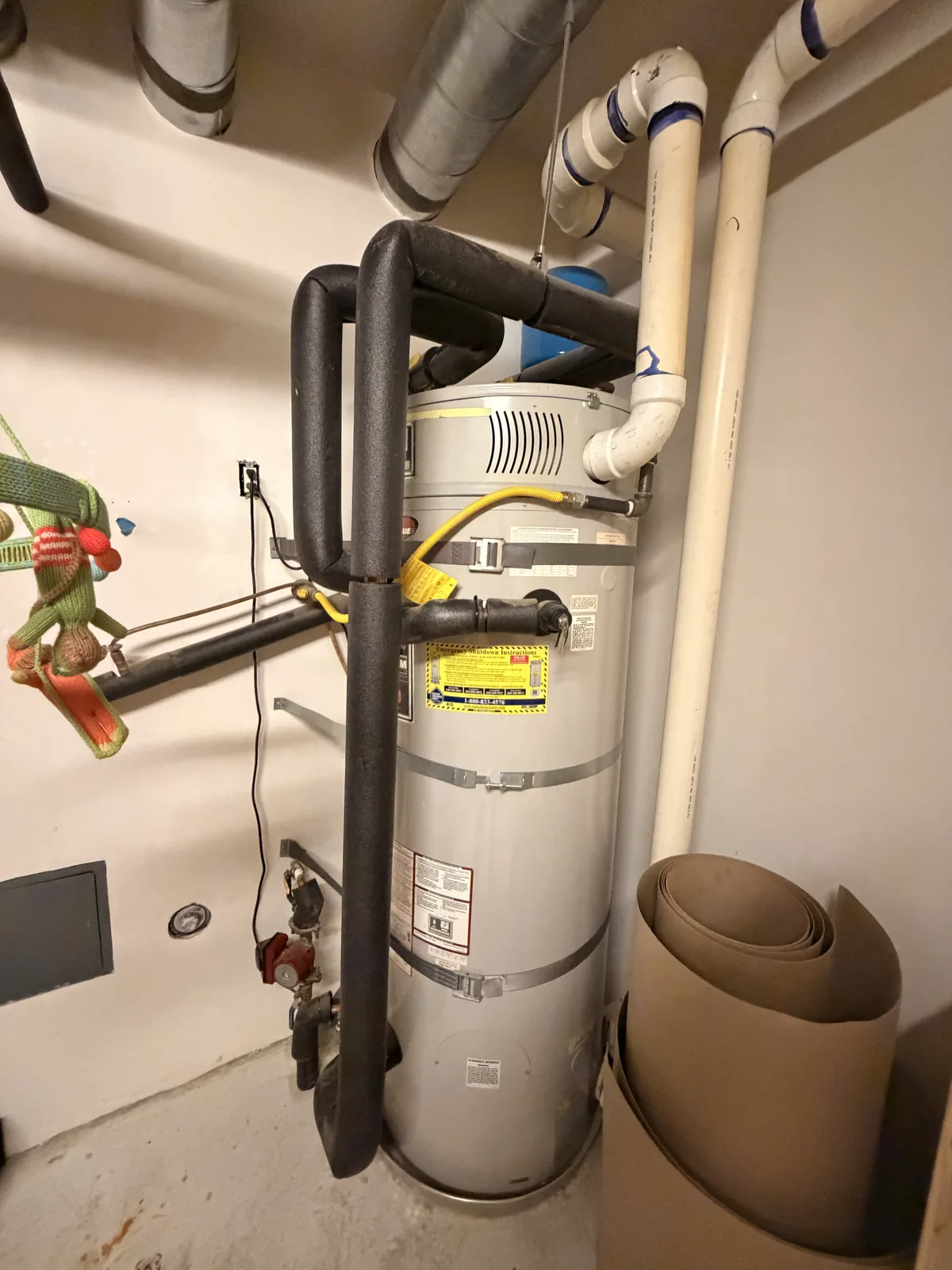 A new gas storage water heater in a closet with an expansion tank above it, a yellow gas connector and new copper lines