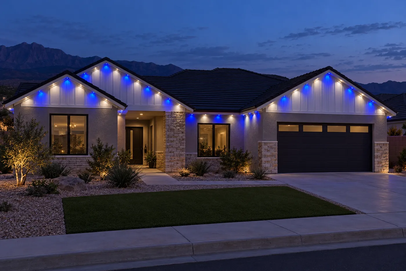 A single-story house with white board-and-batten gables over gray stucco at dusk, eave lights in royal blue and white.