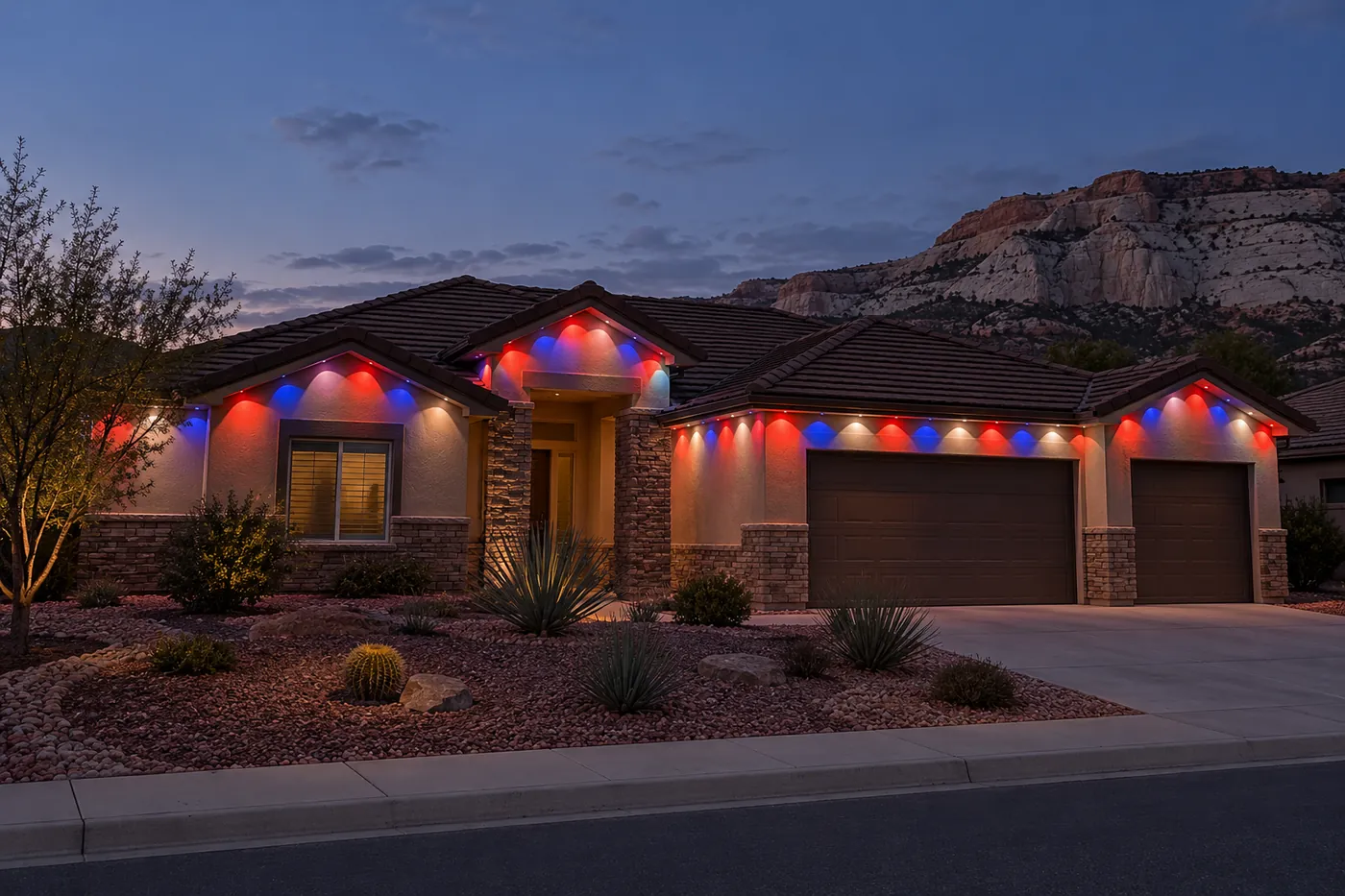 A stucco and stone ranch house with a tile roof at dusk, eave lights repeating red, white and blue, pale cliffs in the distance.